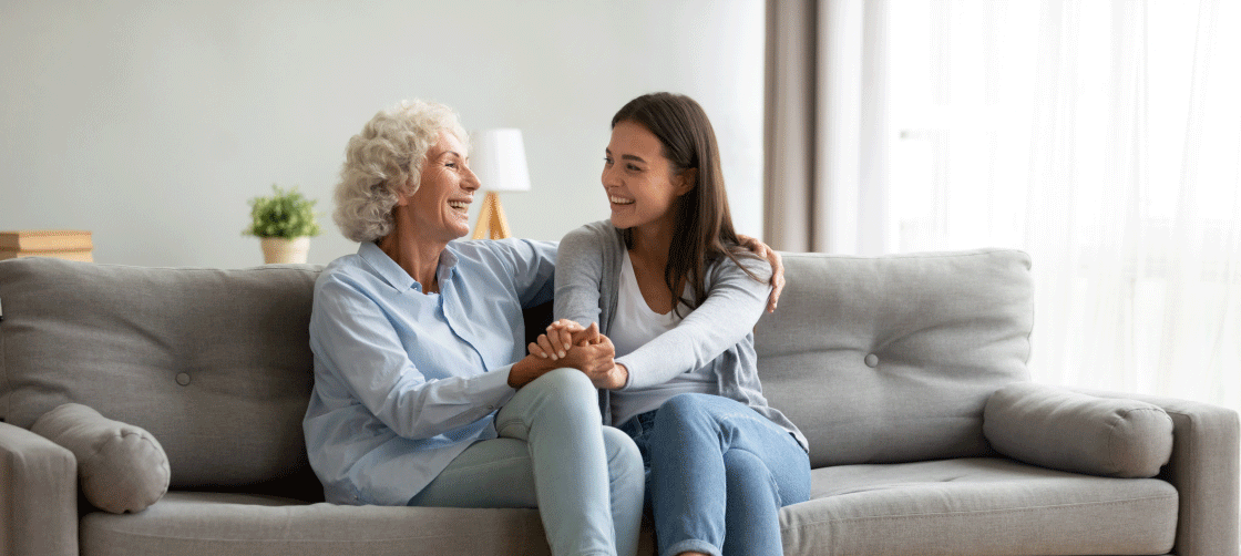 older woman and younger woman holding hands on a couch
