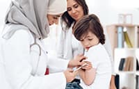 young boy receiving a shot in the arm from a female doctor